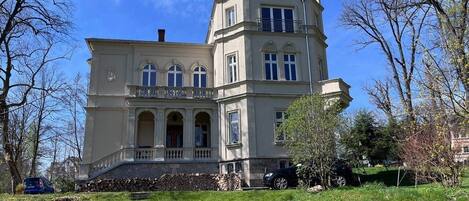 A large, historic building with a symmetrical facade, multiple windows, and a prominent tower.