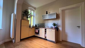 A compact kitchen with wooden flooring, a built-in oven, and a window with a view. - NEW! Vogtland Herberge Auerbach 3 persons + baby (Auerbach)