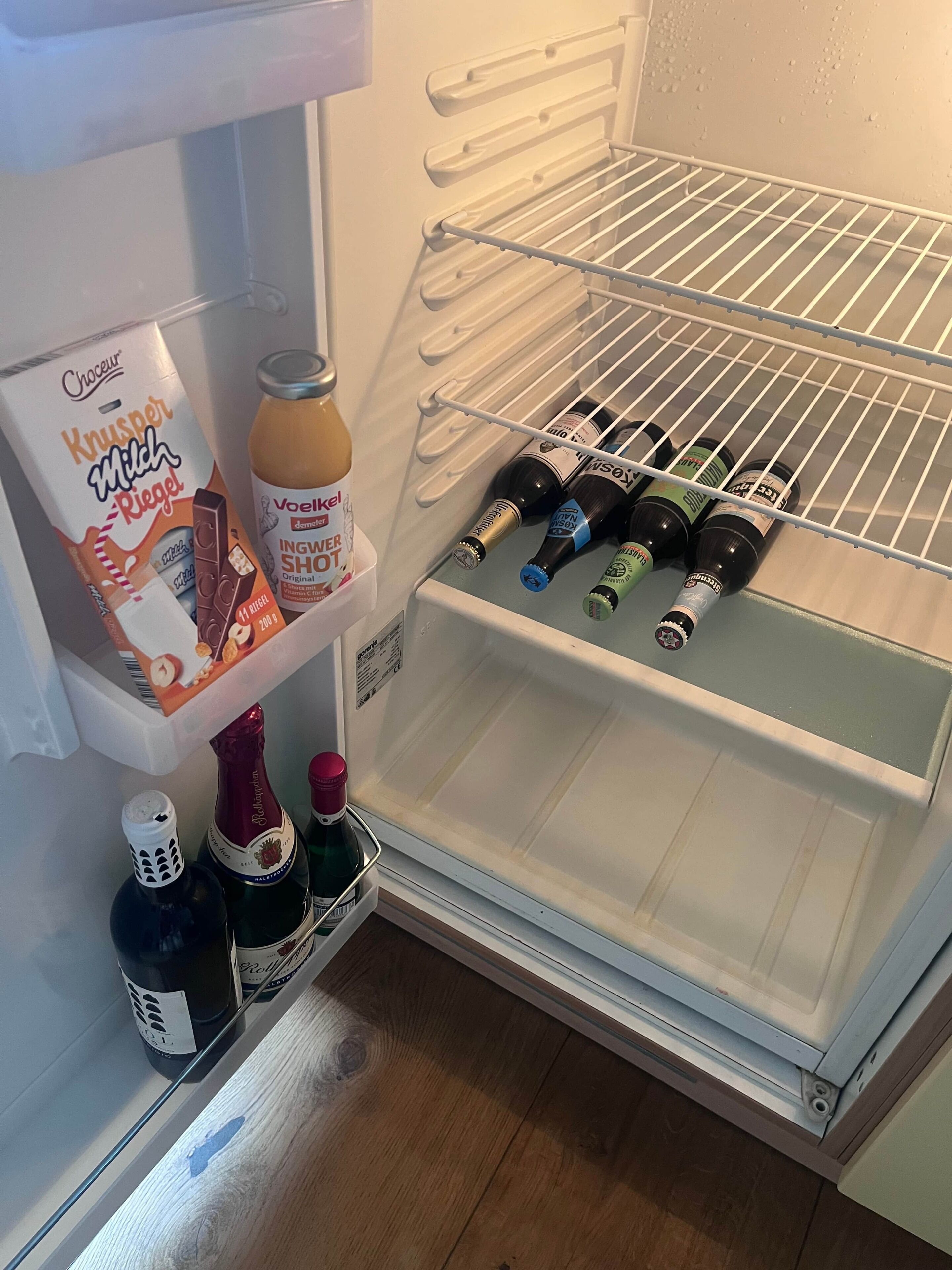 A refrigerator with a milk carton, a bottle of champagne, and several bottles of beer.