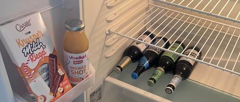 A refrigerator with a milk carton, a bottle of champagne, and several bottles of beer.