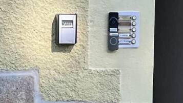 En intercom installeret på væggen og et panel med knapper, sandsynligvis til adgang til eller kommunikation i værelset.