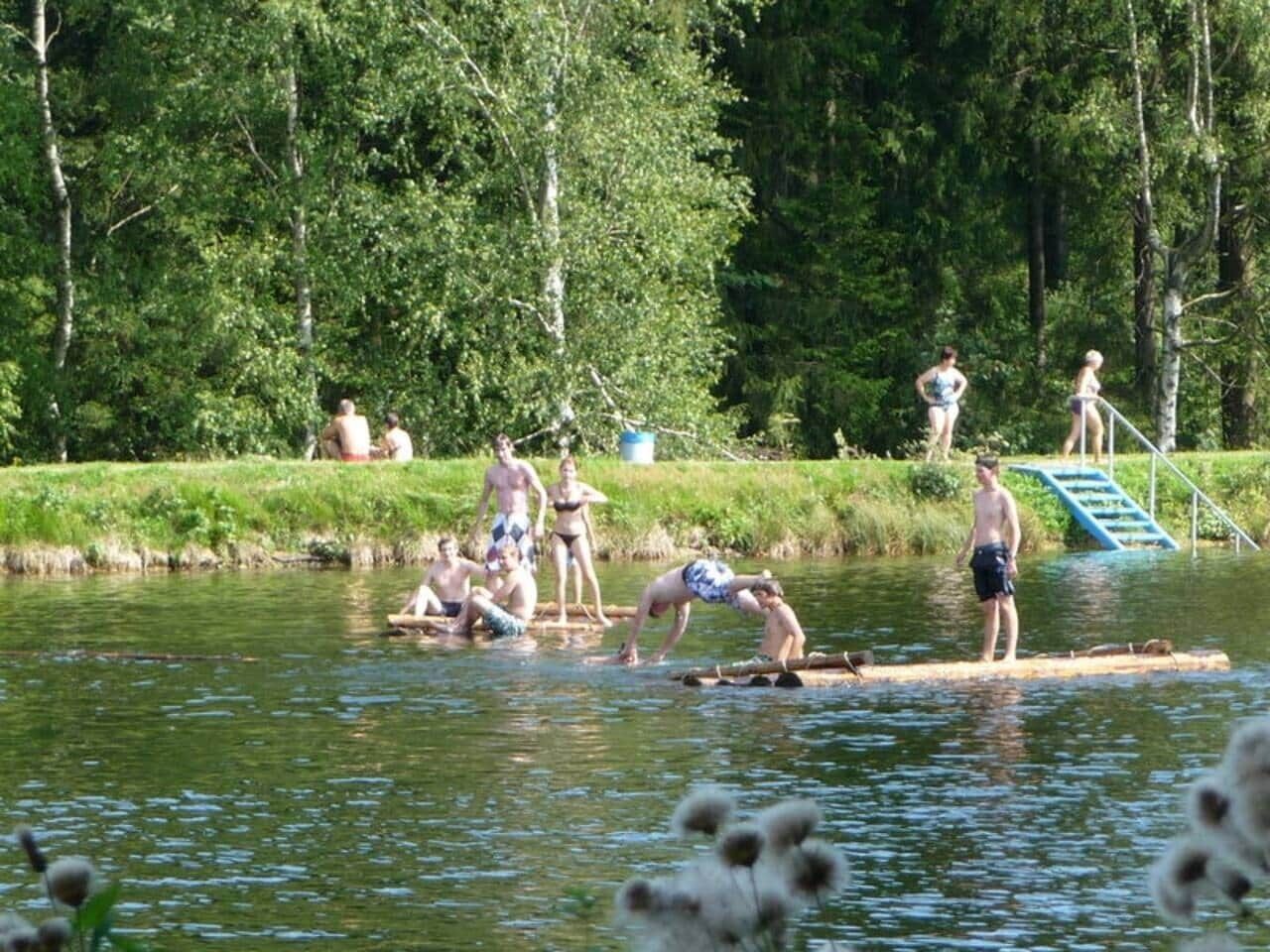 A group of people on a floating platform in a body of water, surrounded by greenery.