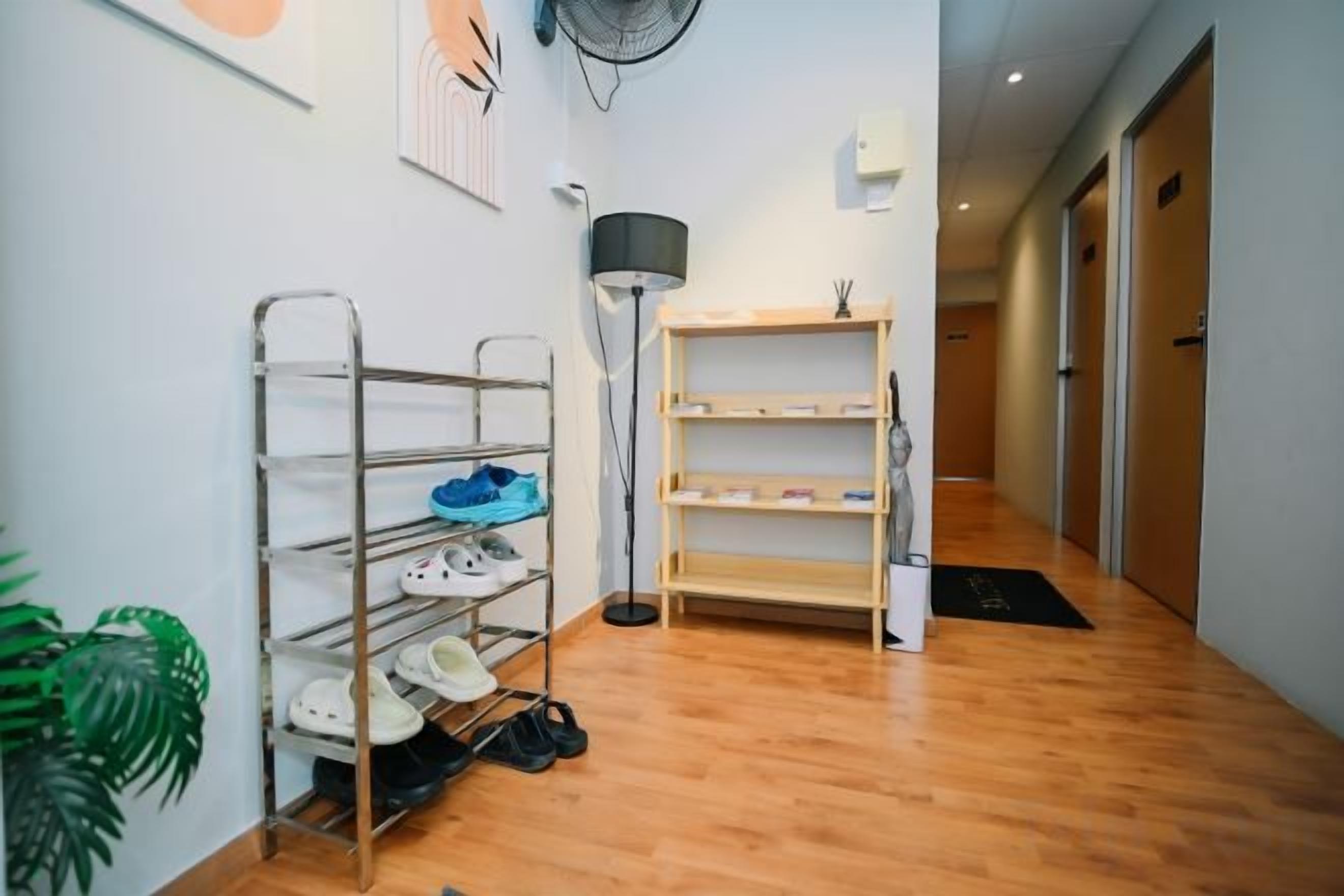 A hallway with a shoe rack, a floor lamp, and a shelf unit.