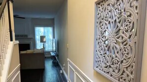 A hallway with dark wooden flooring, white trim, and a decorative wall panel. - Beautiful and cozy house in Duluth! (Duluth)
