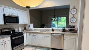 A modern kitchen with white cabinets, stainless steel appliances, a granite countertop, and a window providing natural light. - Beautiful and cozy house in Duluth! (Duluth)