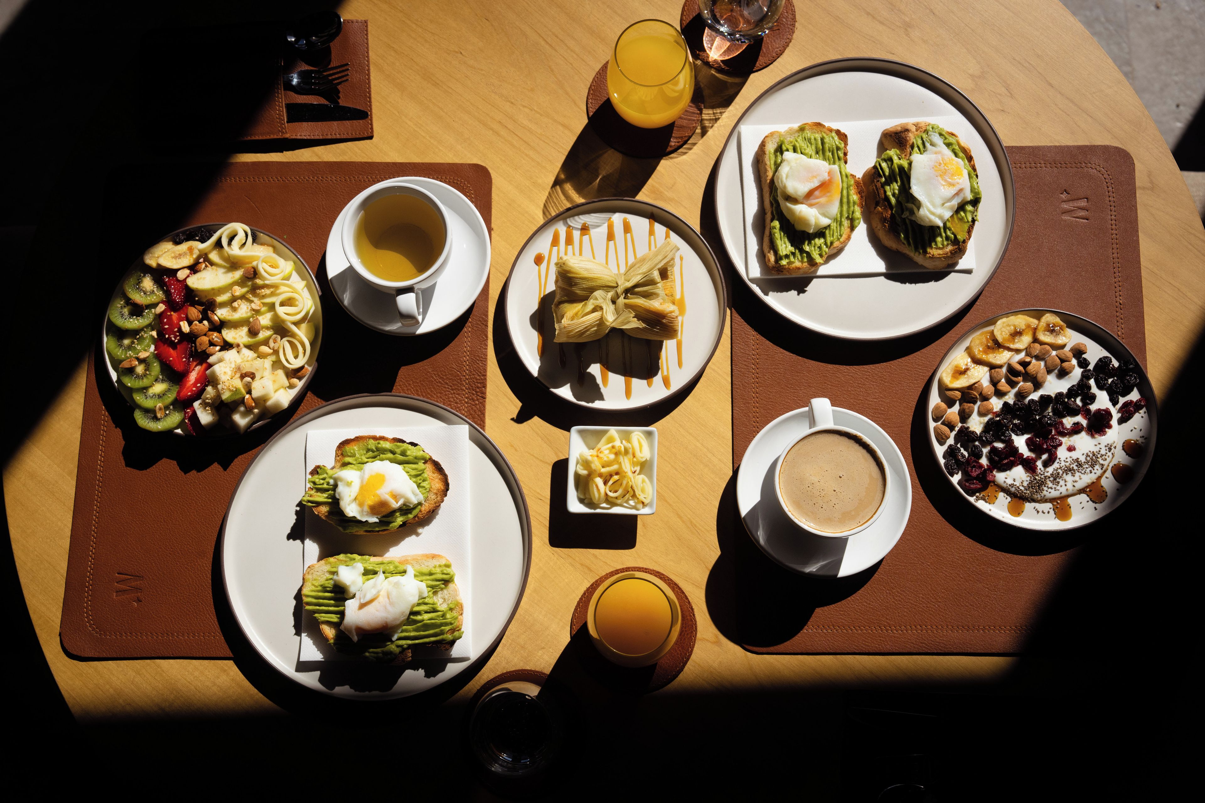 Un desayuno con diferentes platos, bebidas y un mantel de cuero.