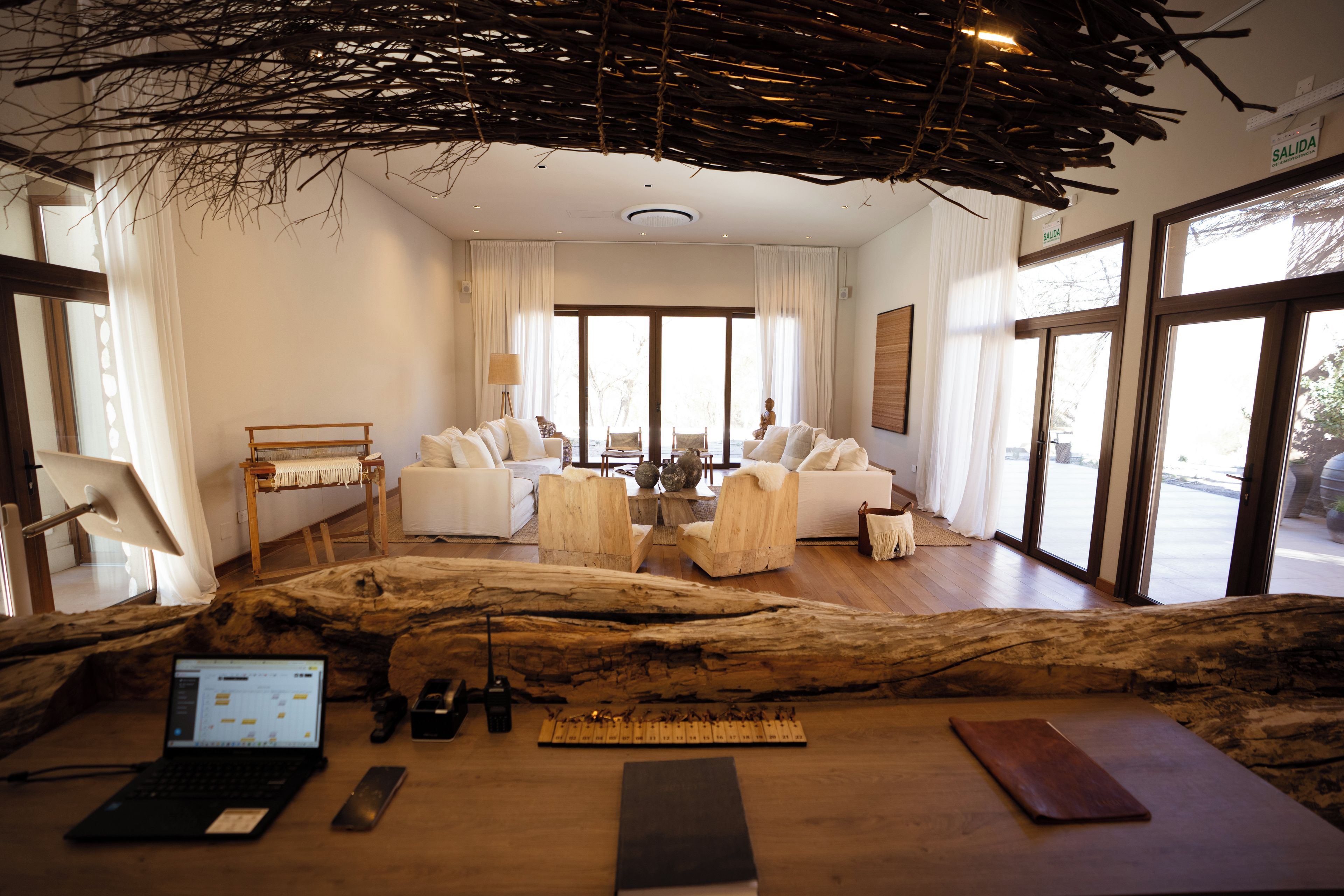 A modern living room with a large wooden sculpture, a sofa set, and a laptop on a wooden table.