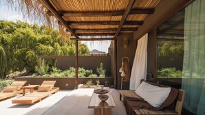 A modern outdoor patio with wooden furniture, a central table, and a view of lush greenery. - Macal Cachi Luxury Lodge (Cachi)