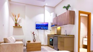 Ein modernes Schlafzimmer mit einem großen Bett, einem kleinen Sofa, einem Holztisch und einem an der Wand befestigten Fernseher.