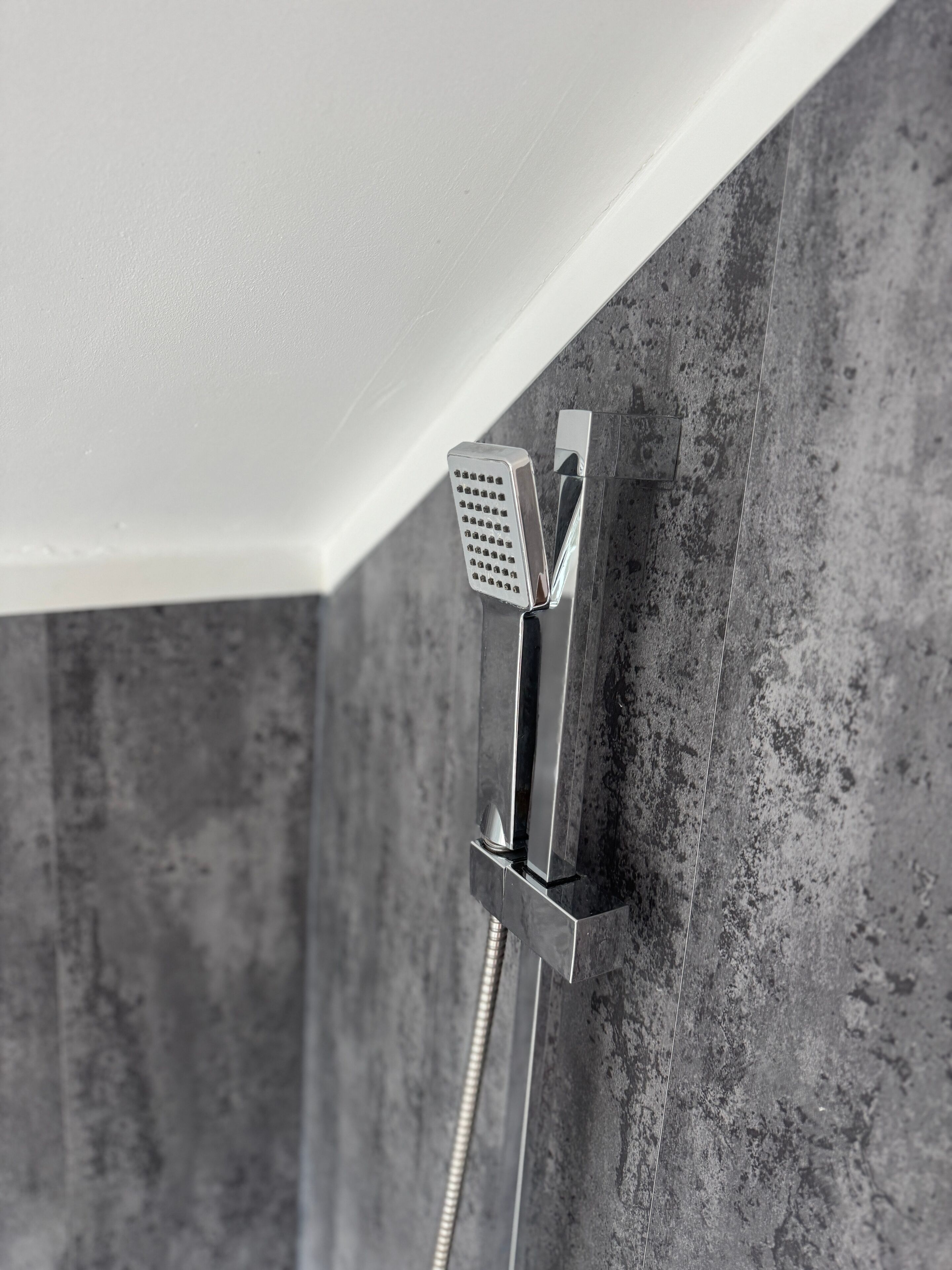 A showerhead mounted on a textured wall with a metallic finish.