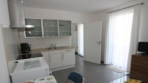 A kitchen with a stove, sink, cabinets, and a dining area with a table and chairs. - "im Schiller" - Holiday Apartment in the Vineyards (Wiesenbronn)
