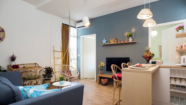 A modern living room with a sofa, chairs, a dining area, and a kitchen with a bar. - Boho-Chic Cozy 2BR - Apt & Balcony in Mar Mikhael (Beirut)