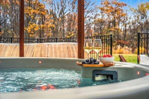 A hot tub with a wooden deck and a wooden fence in the background.