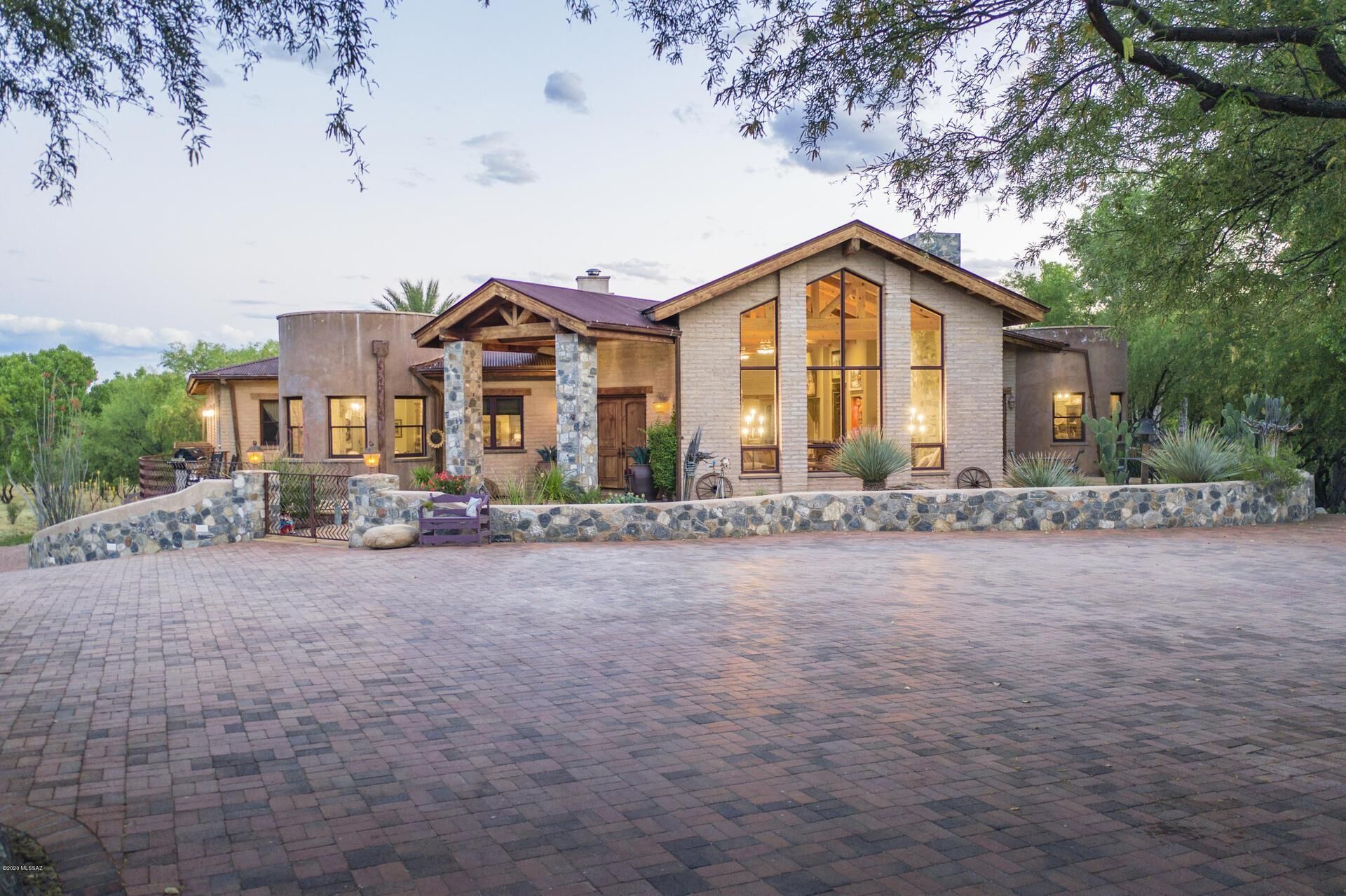 A two-story house with a stone facade, large windows, and a paved driveway.
