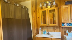 A wooden bathroom with a shower curtain, a sink, a mirror, and a toilet. - 3 Bedroom Lakefront home on Maidstone Lake (Maidstone)