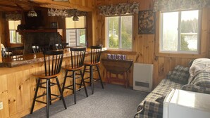 A cabin interior with a bar area, three wooden bar stools, a dining table, and a couch. - 3 Bedroom Lakefront home on Maidstone Lake (Maidstone)