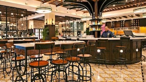 A bar area with round tables, bar stools, and a bartender.