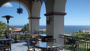 An outdoor patio with tables and chairs, a star-shaped hanging decoration, and a view of the ocean.