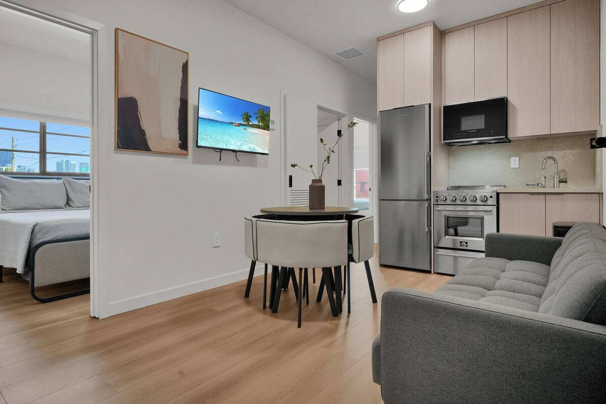 A modern apartment with a dining area, kitchen, and a bed.