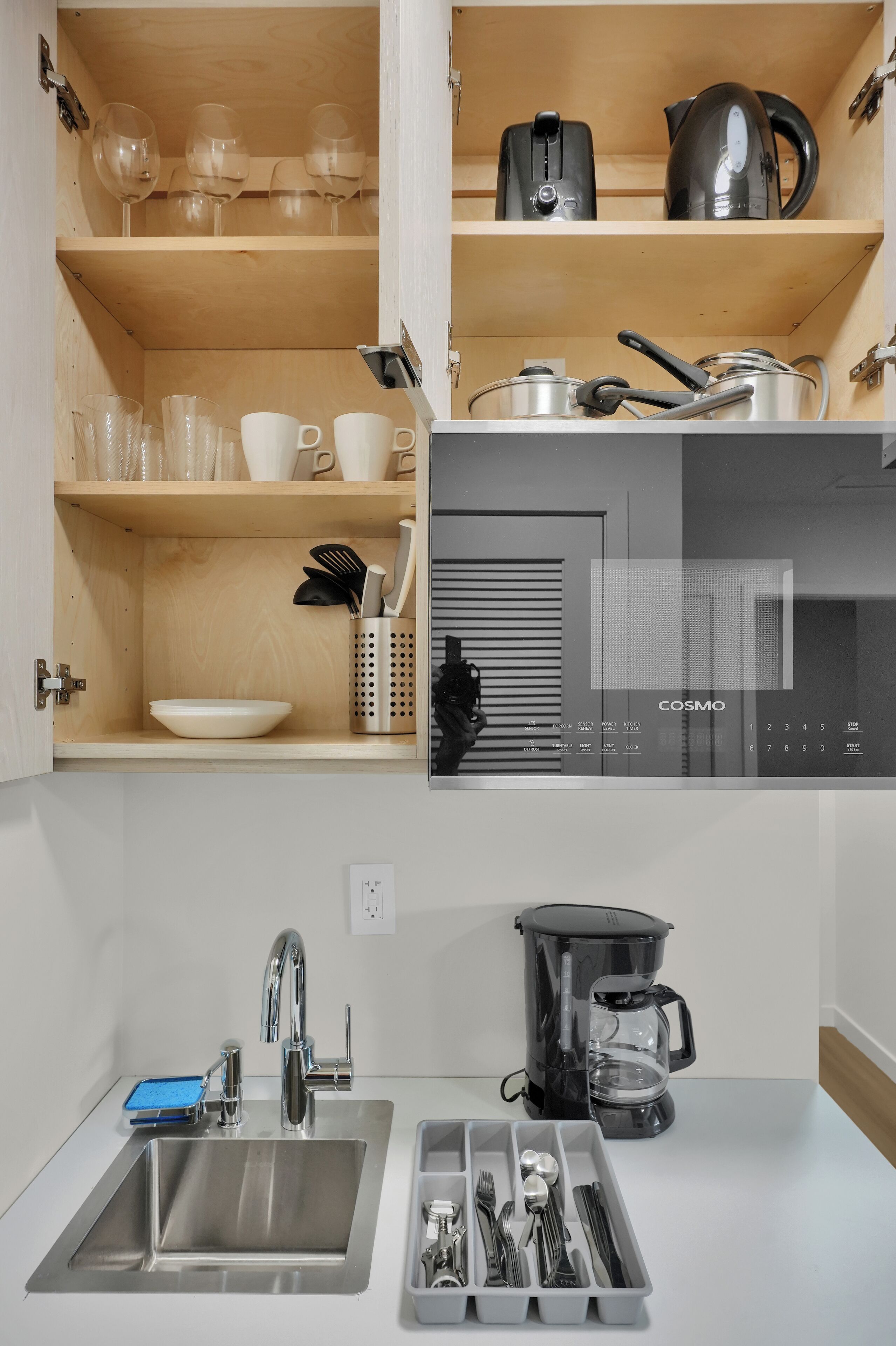 A kitchen with a built-in coffee maker, a sink, and a utensil holder.