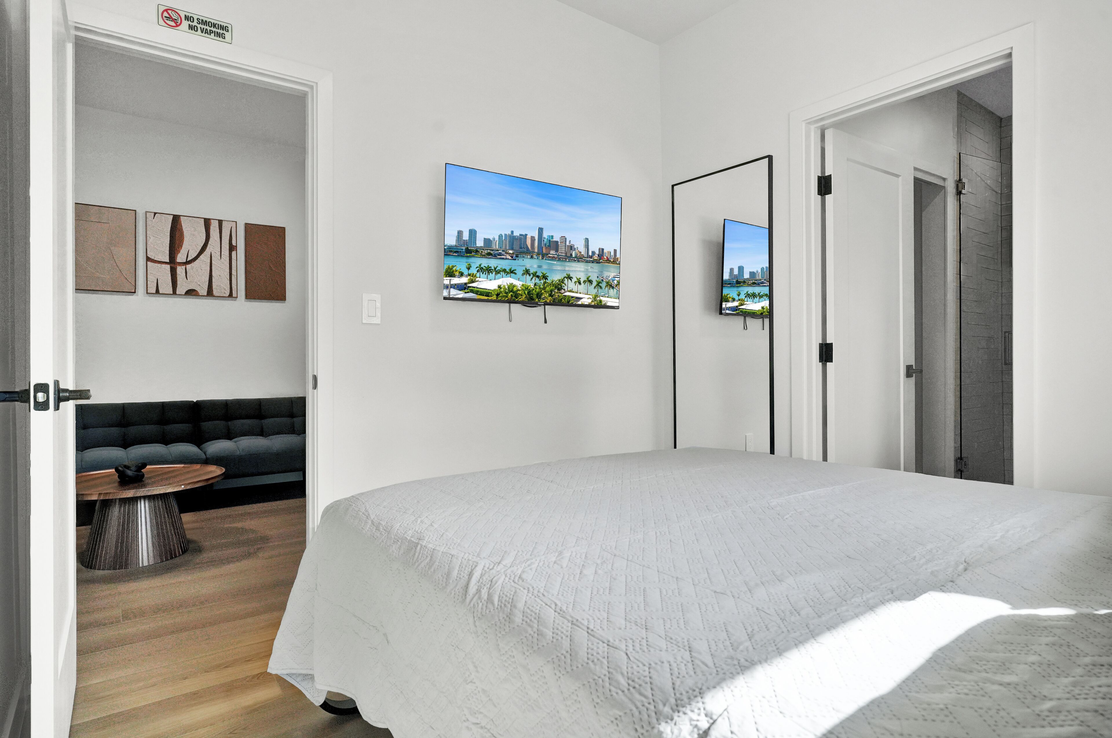 A modern bedroom with a large bed, a cityscape painting, and a mirror.