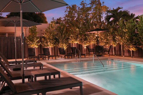 Una piscina al aire libre, sillones reclinables de piscina