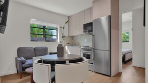 Una cucina moderna con zona pranzo, un divano grigio e vista su spazi verdi.