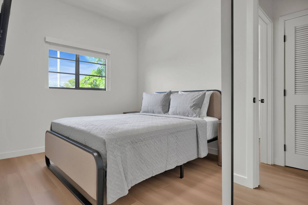 A bedroom with a bed, a window, and a door.