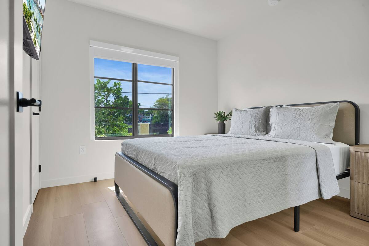 A bedroom with a bed, a window, and a view of greenery outside.