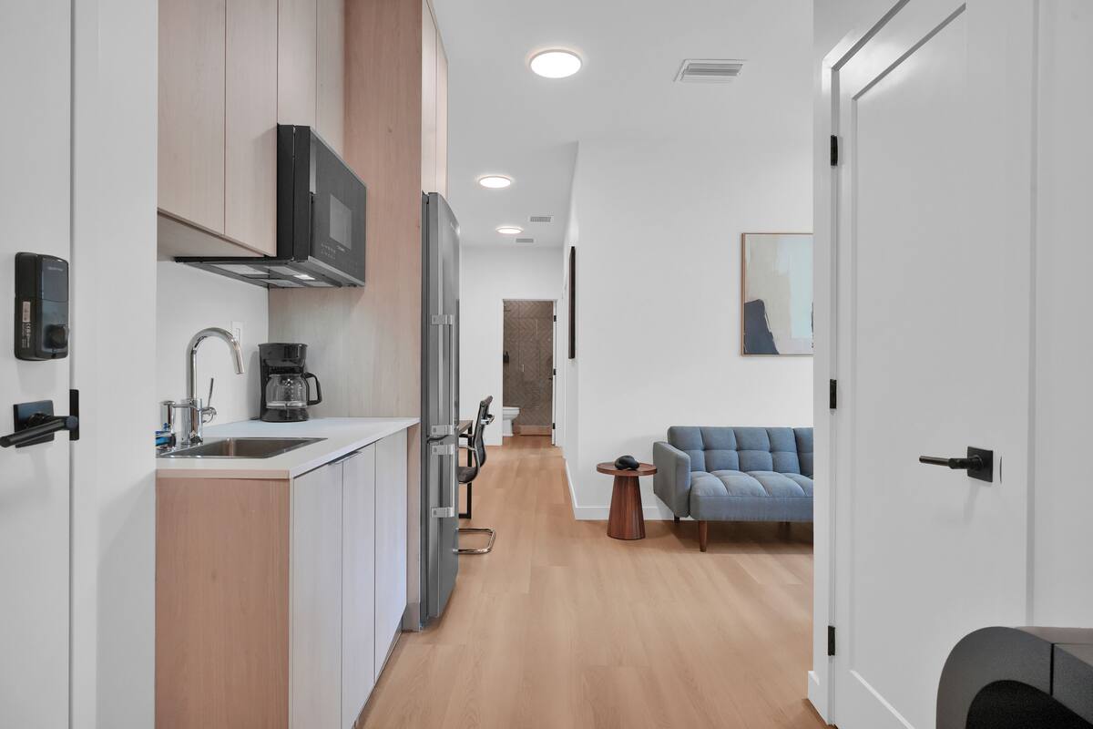 A modern kitchen with a microwave, coffee maker, and a dining area with a sofa and table.