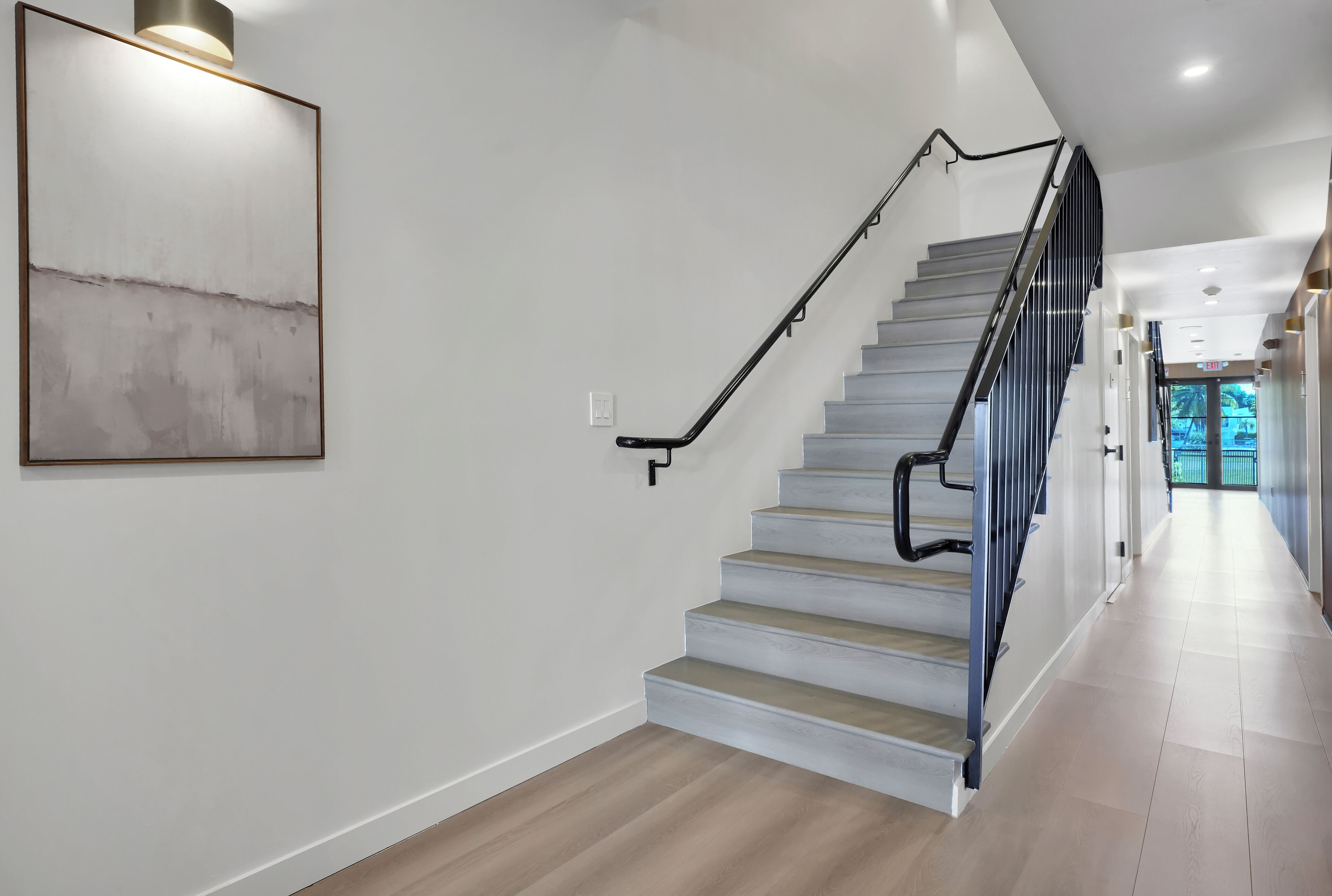 A staircase with a modern design, a light-colored wall, and a wooden floor.