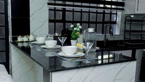 A modern kitchen with a marble countertop, white and gold dinnerware, and a potted plant.