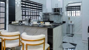 A modern kitchen with marble countertops, a black and white backsplash, and a central island with bar stools.