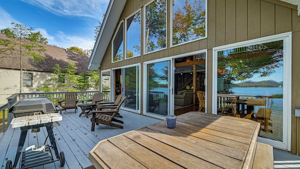 Una terraza con mobiliario de madera, una parrilla y vistas al lago.