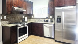 Una cocina moderna con armarios de madera oscura, un refrigerador de acero inoxidable, horno empotrado y encimera de granito.