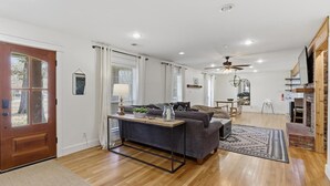 A spacious living area with a wooden floor, a gray sofa, a coffee table, and a fireplace. - The Given House - Modern Midtown Stay (Memphis)