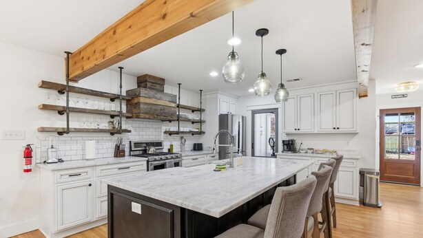 A modern kitchen with white cabinetry, a large island, and pendant lighting. - The Given House - Modern Midtown Stay (Memphis)