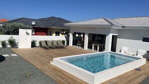 A modern house with a swimming pool, outdoor seating, and a patio area.