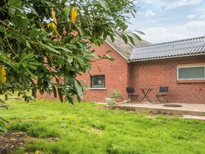 A brick house with a metal roof, a small garden area, and outdoor seating.