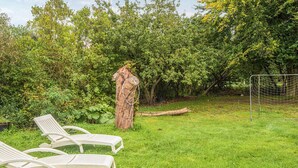 Een gazon met twee witte lounge stoelen, een boom en een voetbaldoel.