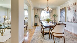A dining area with a long wooden table, six chairs, a chandelier, and a large abstract painting on the wall. - Outdoor Oasis! Luxe Hilltop Home in San Marcos (San Marcos)