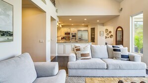 A spacious living room with a grey sofa set, a wooden coffee table, and a view of the kitchen in the background. - Outdoor Oasis! Luxe Hilltop Home in San Marcos (San Marcos)