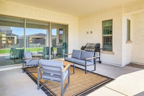 Un patio moderno con dos sofás grises, una mesa de madera y una parrilla.
