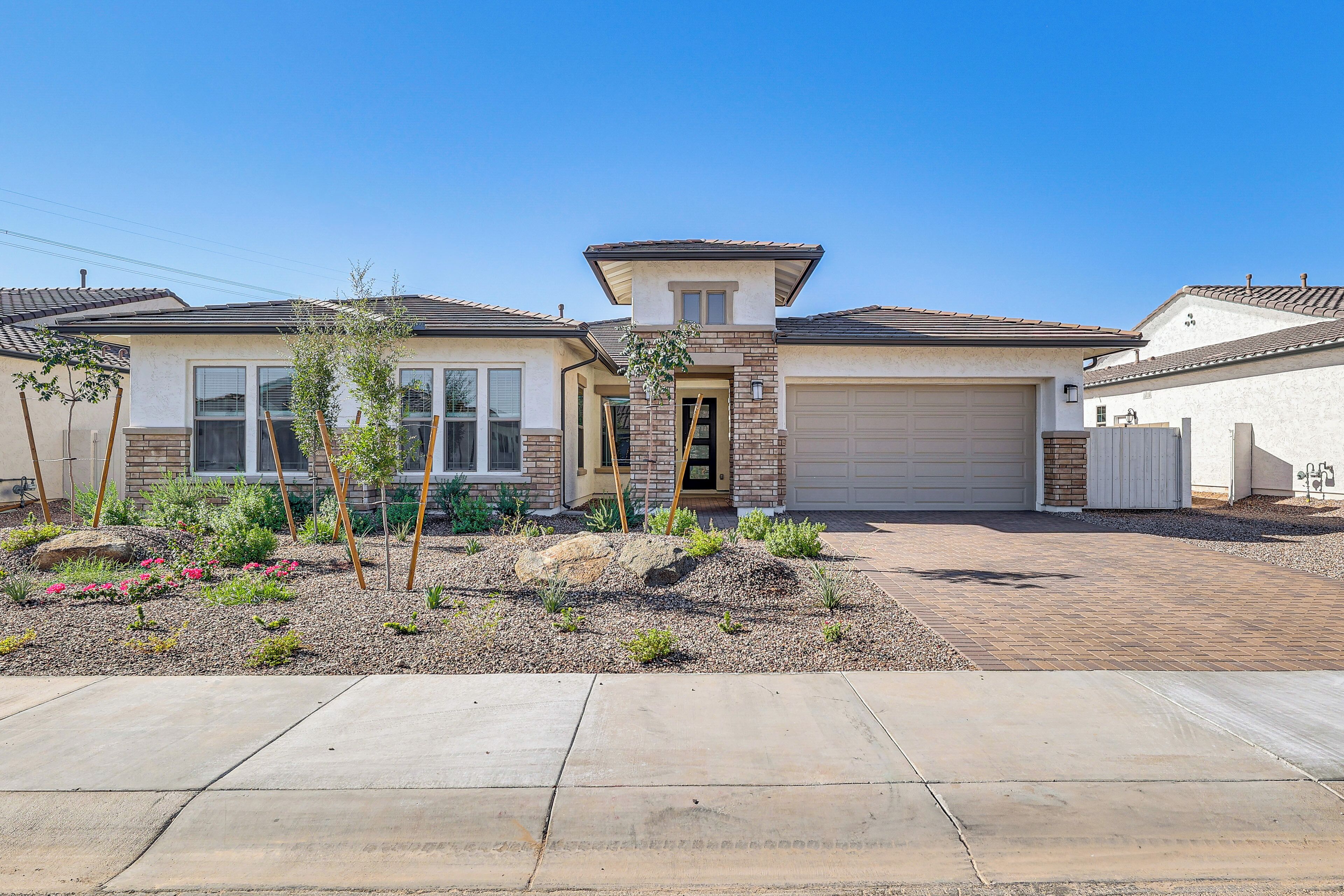 A two-story house with a garage, a front yard with landscaping, and a clear blue sky.