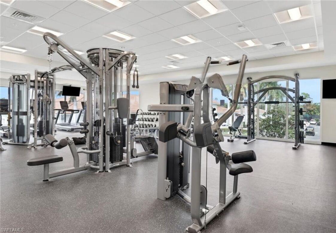 A gym with various exercise machines, a bench, and a large window with a view of the outdoors.