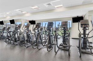 Une salle de sport équipée de nombreux tapis de course et de plusieurs appareils elliptiques disposés en rangées.