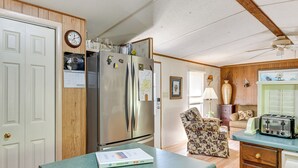 Eine kleine Küche mit einem Kühlschrank, einem Esstisch und einem Stuhl.
