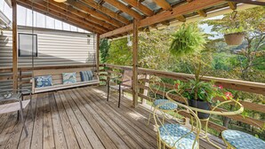 Eine Holzterrasse mit einer Bank, Stühlen und hängenden Pflanzgefäßen.
