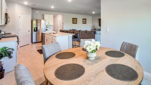 A modern kitchen with a central island, a dining area with a round table and chairs, and a living area with a sofa and chairs. - Family Home w/ Patio & Canal Views in Cape Coral! (Cape Coral)