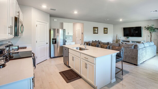A modern kitchen with white cabinetry, a stainless steel refrigerator, and a built-in island with a sink. - Family Home w/ Patio & Canal Views in Cape Coral! (Cape Coral)